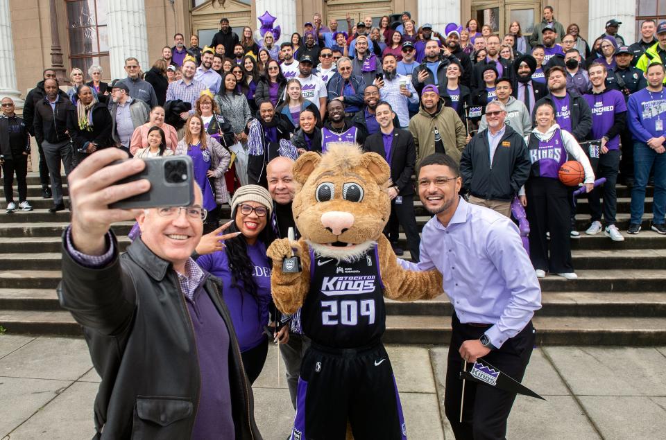 Stockton City Council member Michael Blower, left, takes a selfie with on Mayor Kevin Lincoln  council woman Kimberly Warmsley, city manager Harry Black, Stockton Kings' mascot Dunkston and Stock during a rally at City Hall in honor of the Kings securing a berth in the NBA G League playoffs.