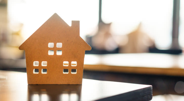 cardboard miniature house on table back-lit by sunlight through a window