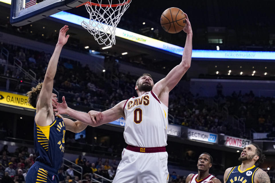 Cleveland Cavaliers forward Kevin Love (0) grabs a rebound over Indiana Pacers guard Chris Duarte (3) during the first half of an NBA basketball game in Indianapolis, Tuesday, March 8, 2022. (AP Photo/Michael Conroy)