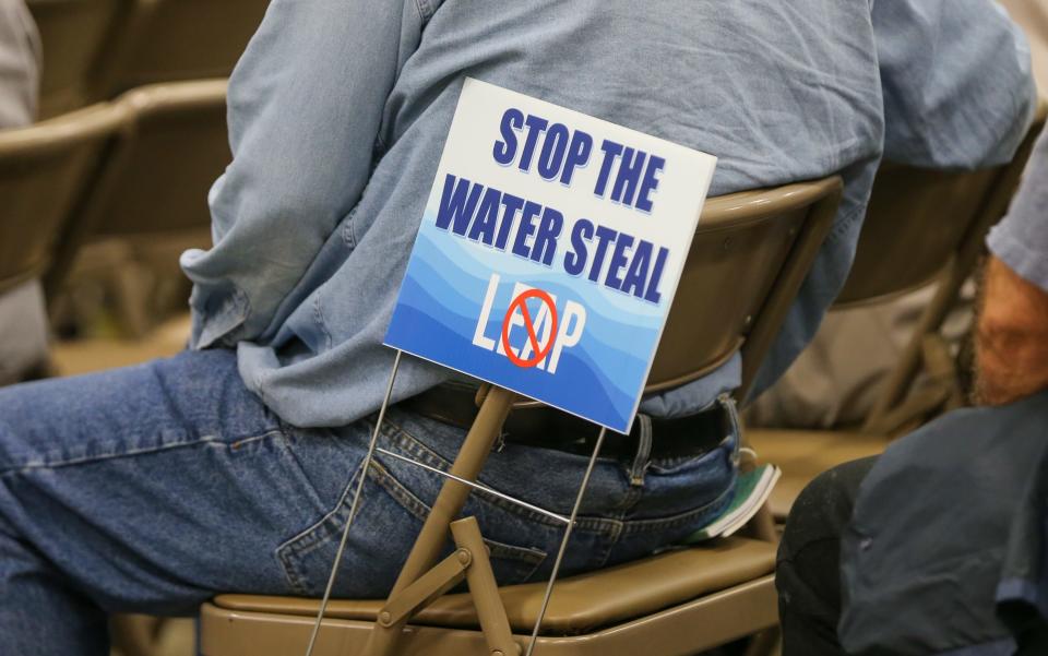 A resident concerned about Wabash River sits next to a sign that says "Stop the water steal" as he attends a public hall to share his concerns regarding Indiana’s Economic Development Corp.'s LEAP project, at the Lafayette Army National Reserve building, on Thursday, Oct. 19, 2023.