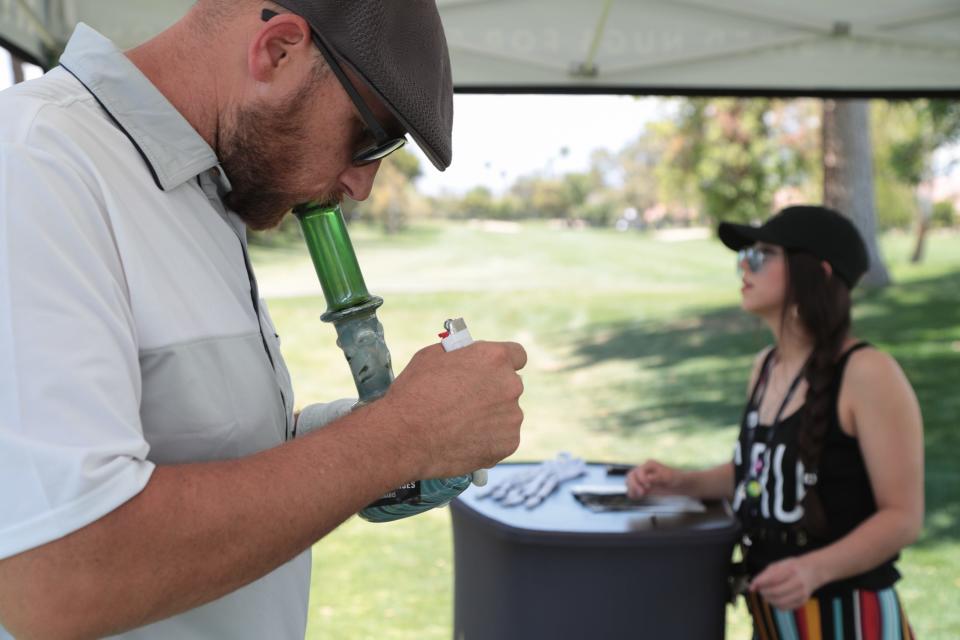 Tom Lopez smokes out of a bong while golfing at the Coachella Valley Cannabis Alliance Network's charity golf tournament, Palm Desert, Calif., May 11, 2019.