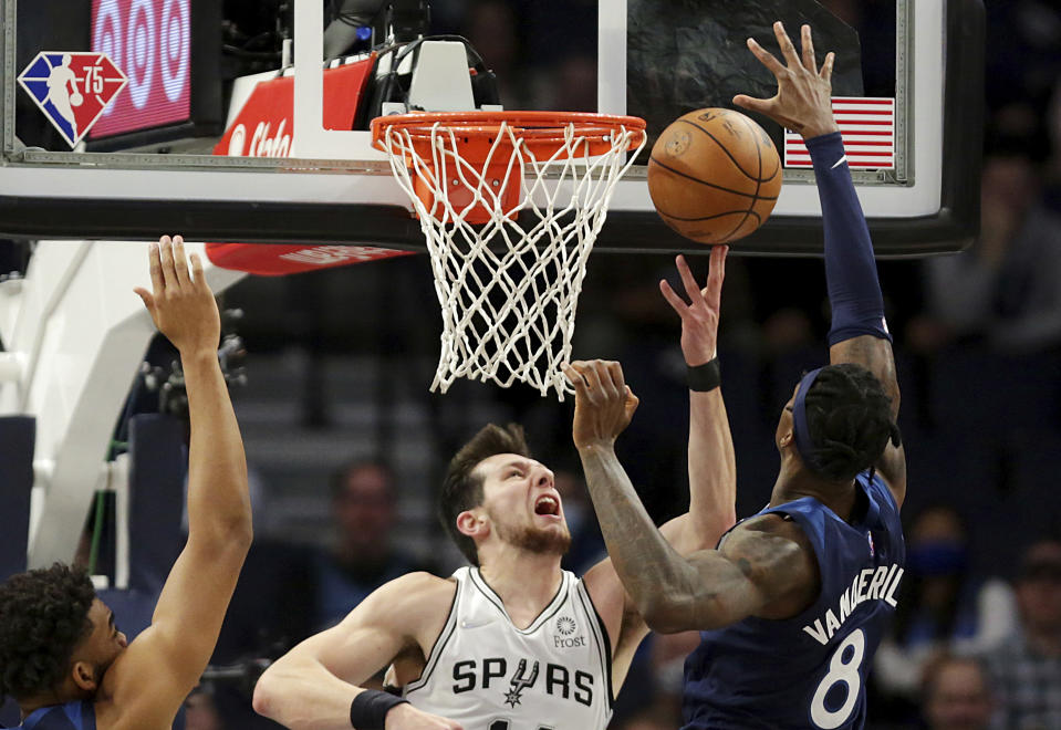 San Antonio Spurs forward Drew Eubanks, center, shoots in front of Minnesota Timberwolves forward Jarred Vanderbilt (8) and center Karl-Anthony Towns, left, in the first half of an NBA basketball game, Thursday, Nov. 18, 2021, in Minneapolis. (AP Photo/Andy Clayton-King)