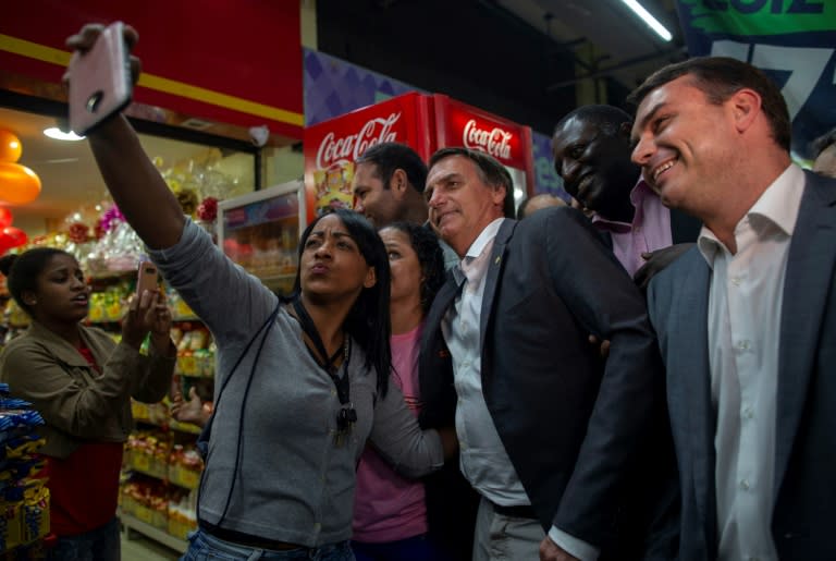Brazilian presidential candidate Jair Bolsonaro (PSL), accompanied by his son Flavio (R), senate candidate for the state of Rio de Janeiro, visits the Mercadao de Madureira, in Rio de Janeiroon August 27, 2018. Bolsonaro is polling in second place for the October 7 first round of voting, after imprisoned frontrunner Luiz Inacio Lula da Silva, and followed by center-right former Sao Paulo governor Geraldo Alckmin and environmentalist Marina Silva