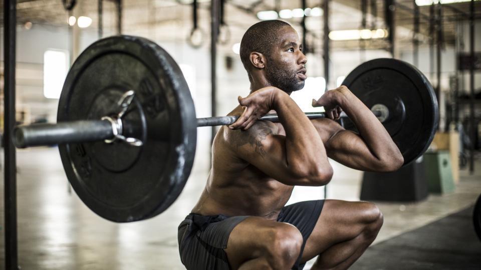 Man doing a barbell front squat in a gym