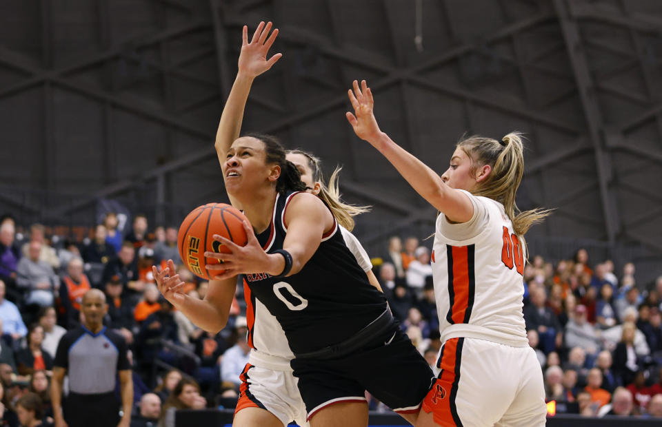 Harvard guard McKenzie Forbes (0) drives to the basket against Princeton forward Ellie Mitchell (00) during the first half of the Ivy League championship NCAA college basketball game, Saturday, March 11, 2023, in Princeton, N.J. (AP Photo/Noah K. Murray)