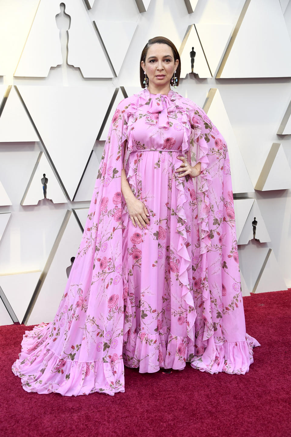 <p>The ‘Bridesmaids’ star added some print to her pink look, wearing a caped, floral dress to the Academy Awards. <em>[Photo: Getty]</em> </p>
