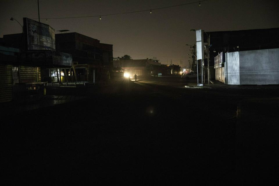 In this May 21, 2019 photo, a man walks in a dark downtown Maracaibo, Venezuela, during a black out. The situation is especially dire in Maracaibo, once known as Venezuela's Saudi Arabia for being at the hub of the country's now-decaying oil industry. Power plants put out a fraction of their potential, and the lights have flickered on and off since late-2017, when a major transmission line burned up. (AP Photo/Rodrigo Abd)