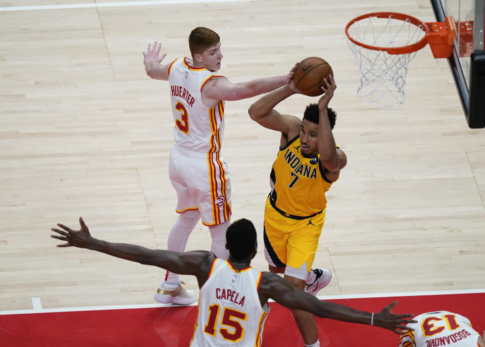 Indiana Pacers Malcolm Brogdon, center, passes the ball against the Atlanta Hawks defense during the first half of an NBA basketball game on Sunday, April 18, 2021, in Atlanta. (AP Photo/Brynn Anderson)