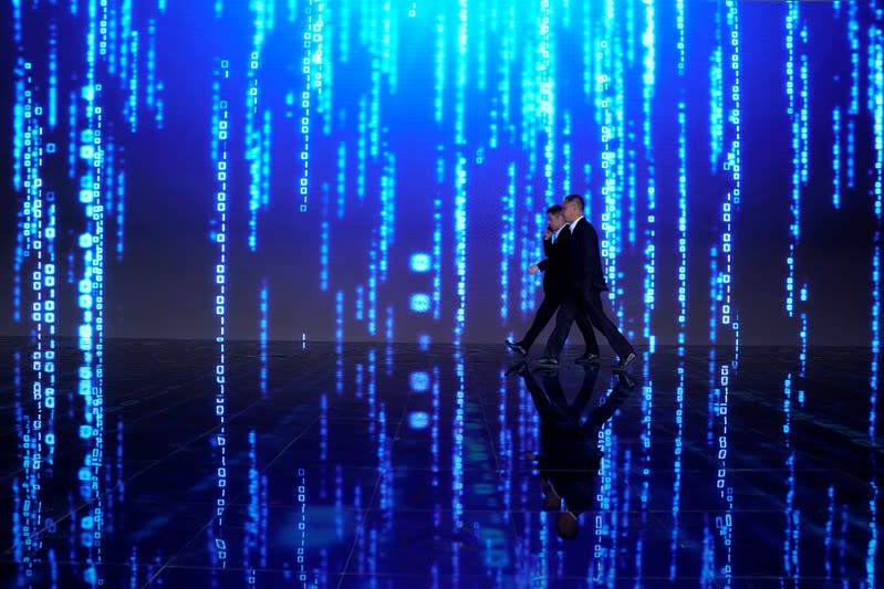 Men walk in front of a screen at the World Internet Conference (WIC) in Wuzhen