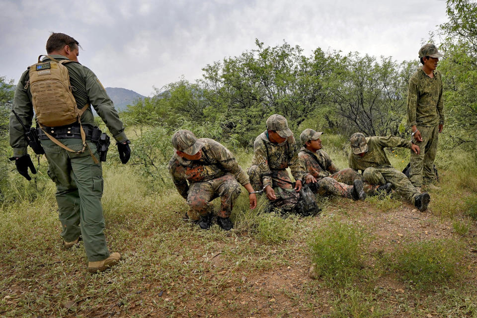 Migrants are handcuffed after being apprehended by U.S. Border Patrol agents in the desert at the base of the Baboquivari Mountains, Thursday, Sept. 8, 2022, near Sasabe, Ariz. The desert region located in the Tucson sector just north of Mexico is one of the deadliest stretches along the international border with rugged desert mountains, uneven topography, washes and triple-digit temperatures in the summer months. Border Patrol agents performed 3,000 rescues in the sector in the past 12 months. (AP Photo/Matt York)
