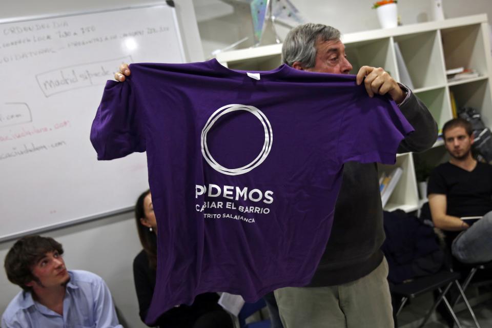 A man shows a Podemos t-shirt for sale to participants of their local assembly at Madrid's Salamanca district December 18, 2014. In just a year since its founding, the party "Podemos" - We Can - has overturned the two party system in place since Spain embraced democracy in the 1970s. It is now polling around even with the ruling People's Party (PP) and main opposition Socialists, and has even led in some polls. The shirt reads, "We can change the neighbourhood. Salamanca district". Picture taken December 18, 2014. REUTERS/Susana Vera (SPAIN - Tags: POLITICS)