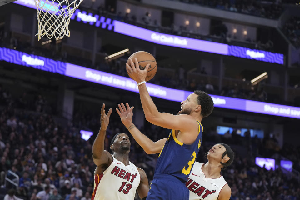 Golden State Warriors guard Stephen Curry (30) drives to the basket as Miami Heat center Bam Adebayo (13) and guard R.J. Hampton defend during the second half of an NBA basketball game Thursday, Dec. 28, 2023, in San Francisco. (AP Photo/Loren Elliott)