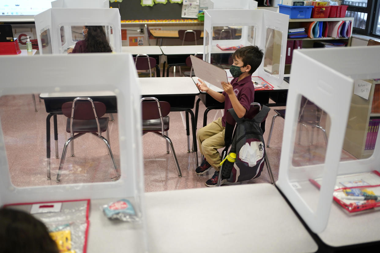 Third graders do their work behind see-though partitions at Christa McAuliffe School in Jersey City, N.J., Thursday, April 29, 2021. Kindergarten through third grade students are returning to their school buildings in Jersey City for their first time in over a year. New Jersey's two largest cities have begun making their return to classrooms in person after working remotely because of the COVID-19 outbreak. Students in Jersey City began returning to school today, just days after Newark officials said they were expanding in-person instruction to four days a week, up from two. (AP Photo/Seth Wenig)