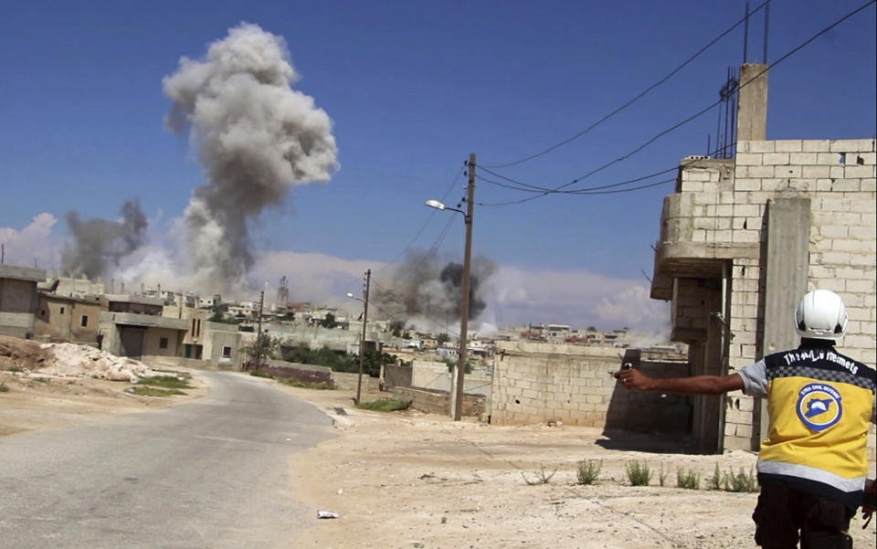 This photo provided by the Syrian Civil Defense group known as the White Helmets, shows a civil defense worker as smoke rises from a Syrian government airstrike, in Hobeit village, near Idlib, Syria, Sunday, Sept. 9, 2018. The White Helmets and a conflict monitoring group said Sunday that government and Russian forces have resumed their bombing of the opposition's last stretch of territory in the country, killing an infant girl and damaging a hospital. (Syrian Civil Defense White Helmets via AP)