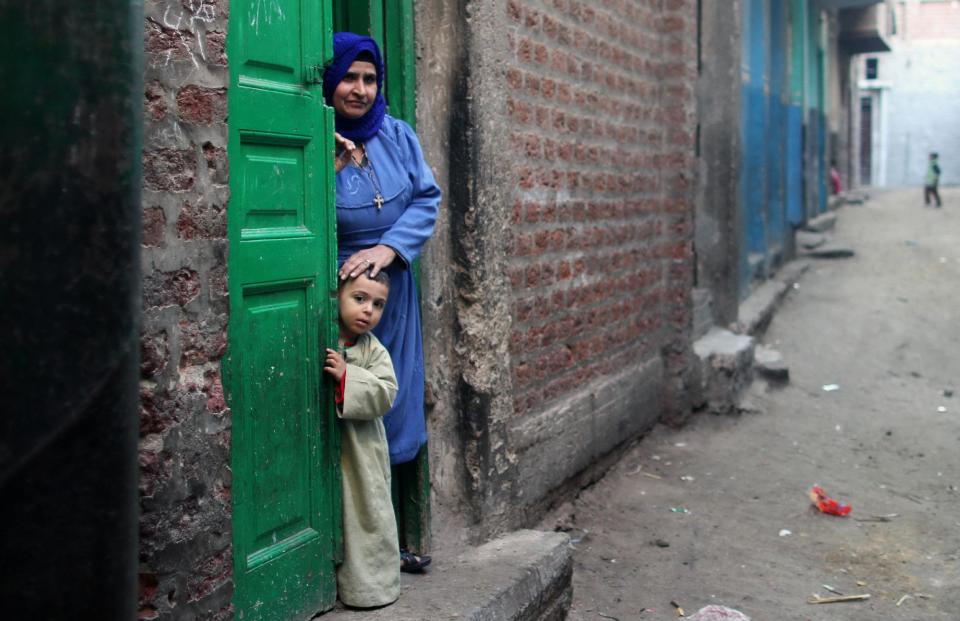 A Christian woman and her son stand in the doorway of their home in Dalga village of Minya, Egypt, Wednesday, Jan. 15, 2014 on the second day of voting in the country's constitutional referendum. Through violence or intimidation, Islamists in villages like this one used violence or intimidation to stop Christians from voting "no" to a 2012 constitution that had paved the way for the creation of an Islamic state. This time around, no one is stopping the Christians and they are voting "yes" on a new charter that criminalizes discrimination and instructs the next legislature to ease restrictions on building churches. (AP Photo/Roger Anis, El Shorouk Newspaper) EGYPT OUT