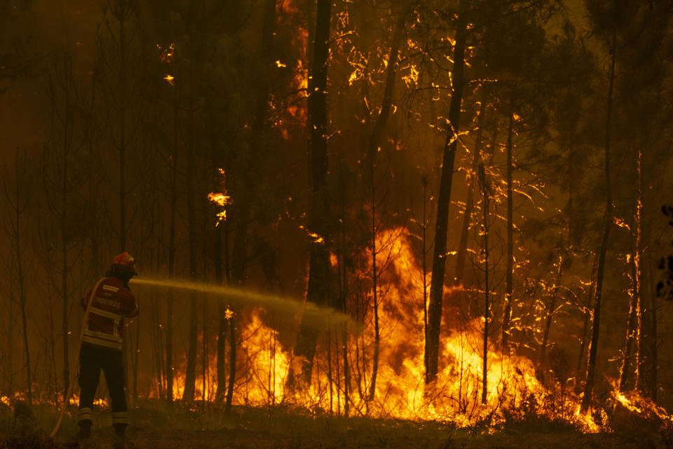 Firefighters try to extinguish a wildfire at the village of Chaveira, near Macao, in central Portugal on Monday, July 22, 2019. More than 1,000 firefighters are battling a major wildfire amid scorching temperatures in Portugal, where forest blazes wreak destruction every summer. About 90% of the fire area in the Castelo Branco district, 200 kilometers (about 125 miles) northeast of the capital Lisbon, has been brought under control during cooler overnight temperatures, according to a local Civil Protection Agency commander. (AP Photo/Sergio Azenha)