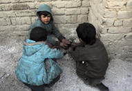 Internally displaced boys warm themselves near a fire outside their temporary home in the city of Kabul, Afghanistan, Wednesday, Dec. 30, 2020. Save the Children has warned that more than 300,000 Afghan children face freezing winter conditions that could lead to illness, in the worst cases death, without proper winter clothing and heating. (AP Photo/Rahmat Gul)