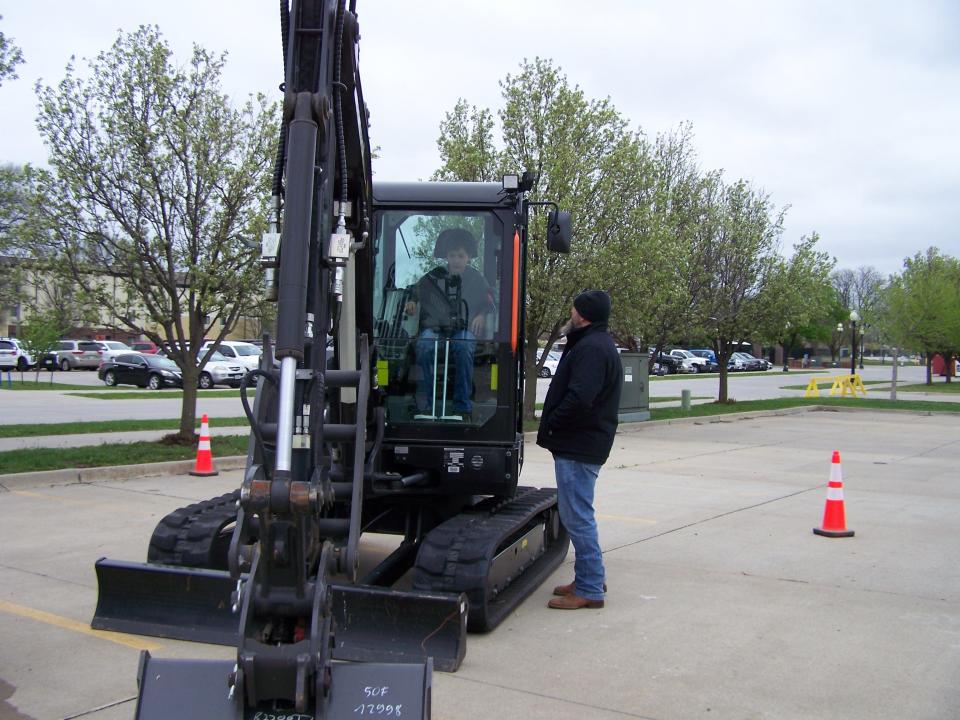 Magnus Aljets, a freshman at Manson Northwest Weber High School, gets a chance to stack tires with an excavator while Aaron Slota (in cab) of Housby Equipment coaches