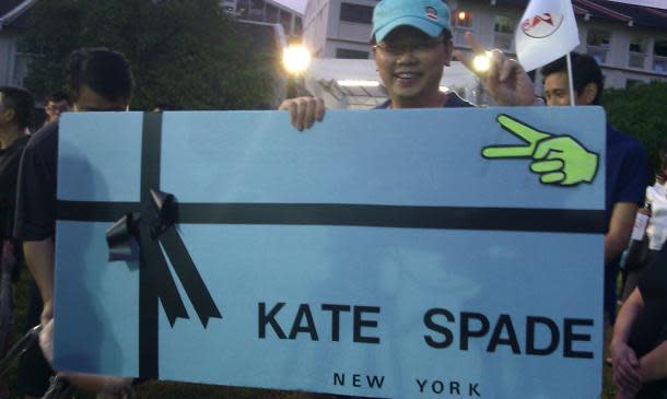 Reno Tan, a Marine Parade resident, made this Kate Spade board to make a statement at the rallies he attended. Here, he poses with it at an SPP rally. (Yahoo! photo / Jeanette Tan)