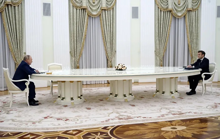 Putin with French President Emmanuel Macron at opposite ends of a very long table.