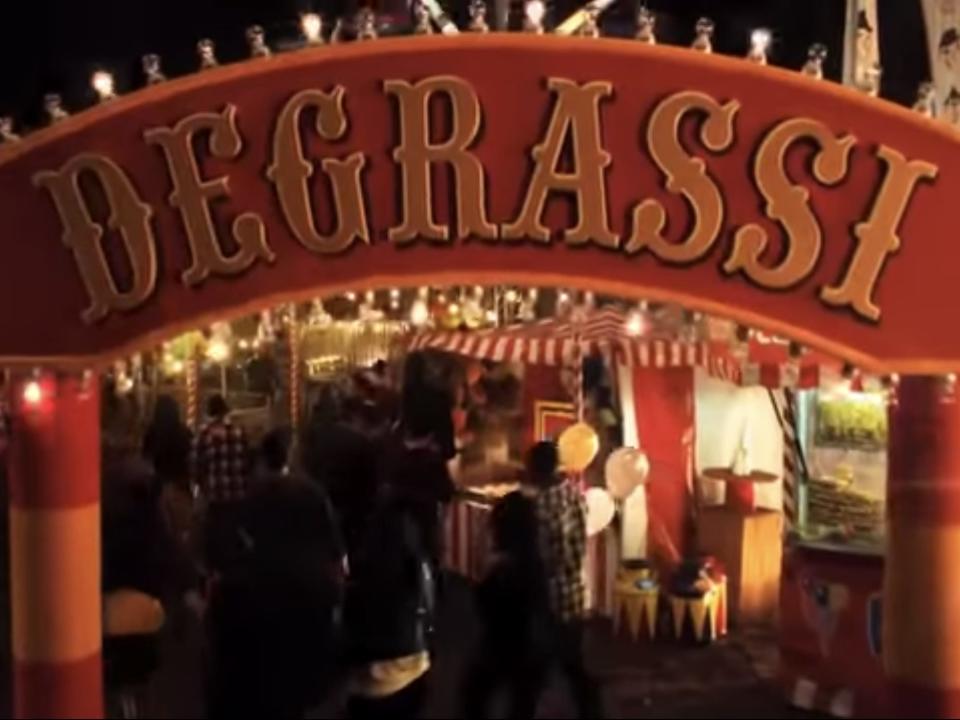 red degrassi sign at the entrance to a carnival, shark in the water promo video