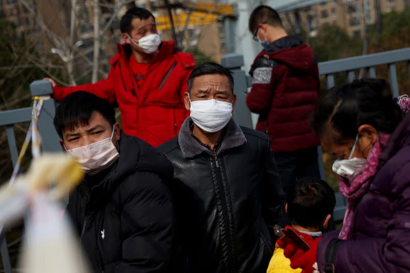 People coming from the Hubei province wait at a checkpoint at the Jiujiang Yangtze River Bridge in Jiujiang