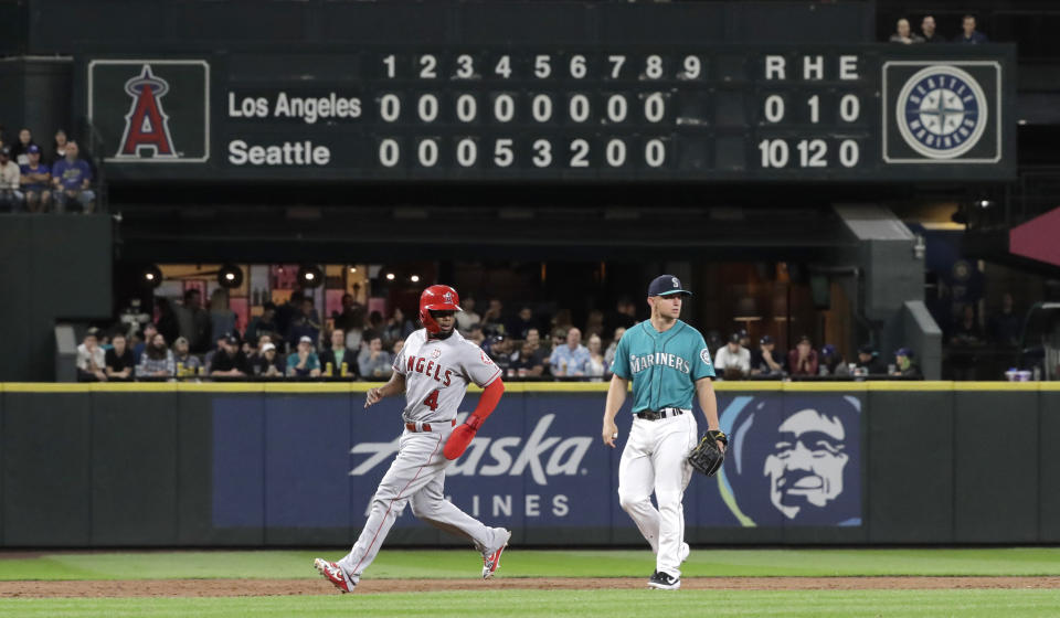 With the manual scoreboard in the background, Los Angeles Angels' Luis Rengifo (4) heads to third base past Seattle Mariners third baseman Kyle Seager on a groundout by Matt Thaiss during the ninth inning of a baseball game, Friday, July 19, 2019, in Seattle. Earlier in the inning, Rengifo hit a single to break up a perfect game being thrown by Mariners pitcher Mike Leake. (AP Photo/Ted S. Warren)