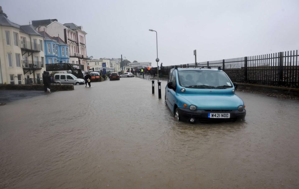 A view of a car parked on a flooded street by the sea wall, in Dawlish, England, Wednesday, Feb. 5, 2014. where high tides and strong winds have created havoc in the Devonshire town disrupting road and rail networks and damaging property. (AP Photo/PA, Ben Birchall) UNITED KINGDOM OUT
