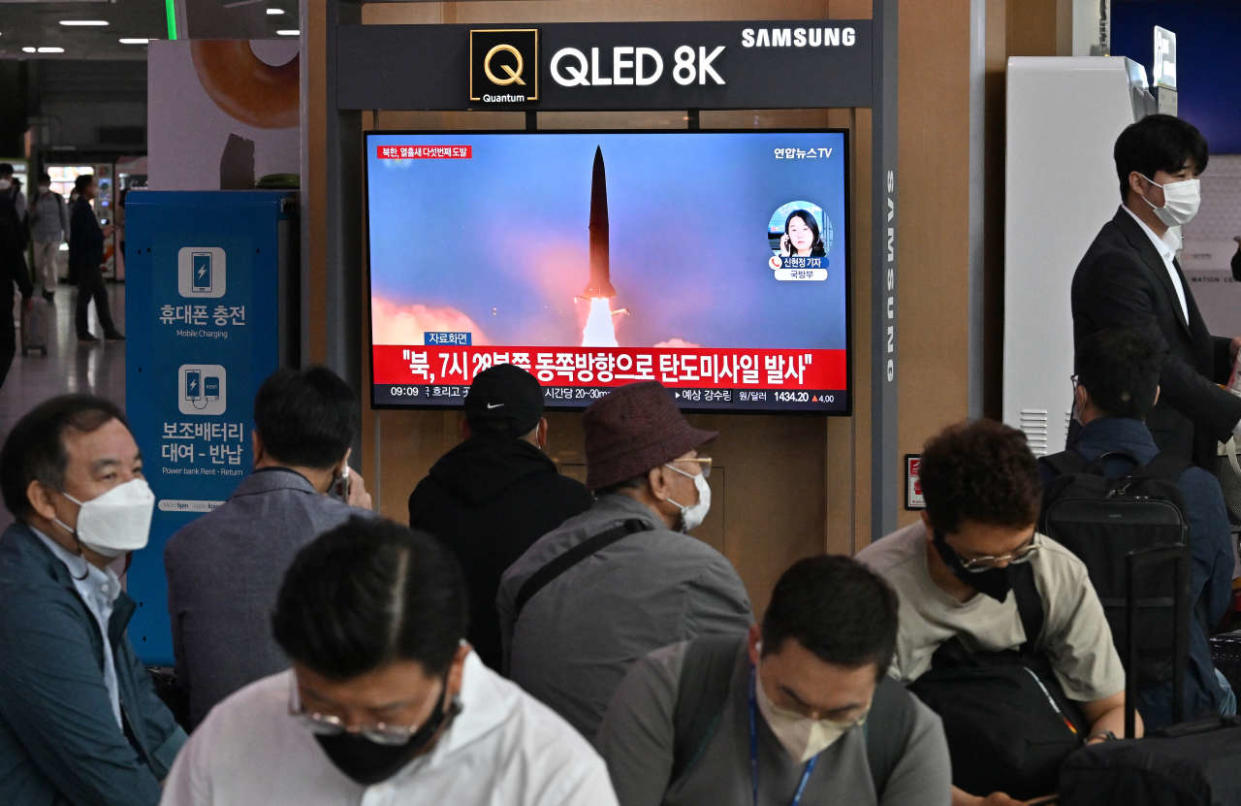 People watch a television screen showing a news broadcast with file footage of a North Korean missile test, at a railway station in Seoul on October 4, 2022. - North Korea fired a mid-range ballistic missile on October 4, which flew over Japan, Seoul and Tokyo said, a significant escalation as Pyongyang ramps up its record-breaking weapons-testing blitz. (Photo by Jung Yeon-je / AFP)