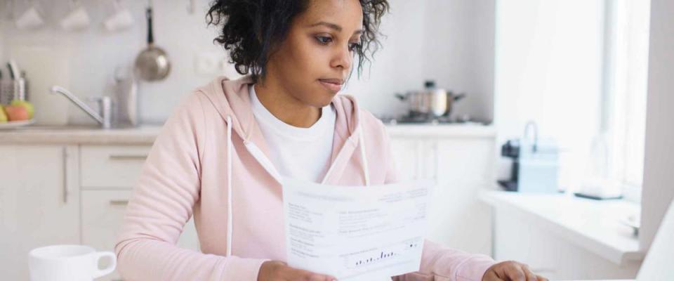 Concentrated young african american female student using online banking application with hand on touchpad, looking at screen of his laptop, trying to make payment for university education