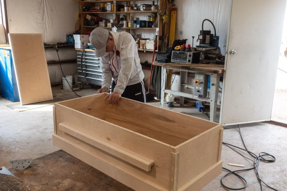 One of Rhonita Miller’s nephews sands a coffin that was made for her by family members. | César Rodríguez—El País