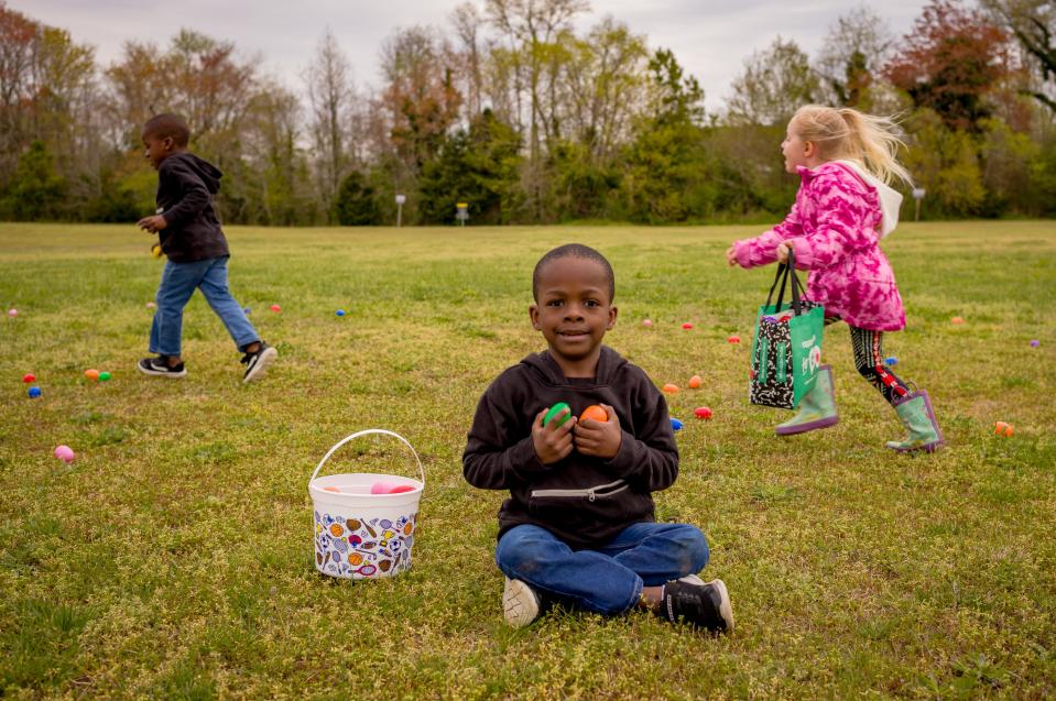 An egg hunter takes a moment to show off his haul, while others race behind him to get their share at the Easter egg hunt in Sawmill Park in Accomac.