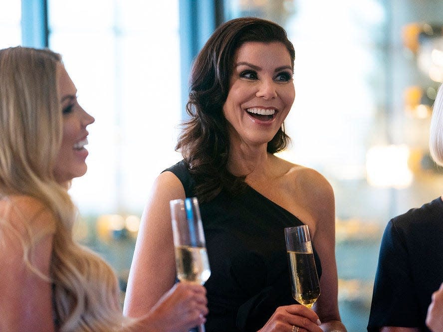 Heather Dubrow wearing a black dress and smiling.