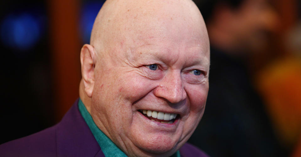 Bert Newton smiling while wearing a purple suit