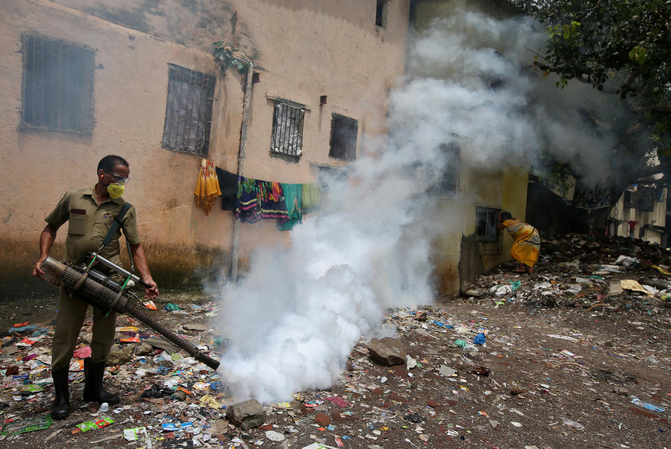 A municipal worker fumigates a slum area to prevent the spread of dengue fever and other mosquito-borne diseases in Mumbai, India.