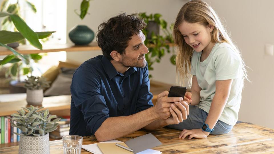 man showing smart phone to daughter while discussing at home