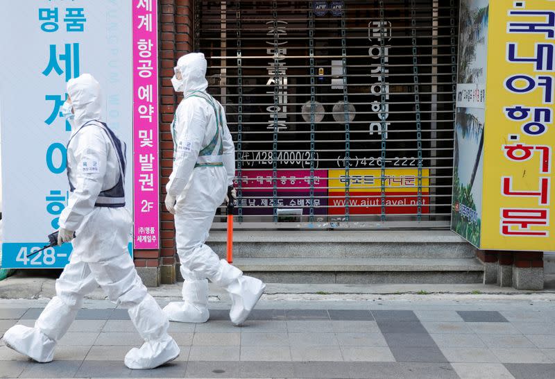 South Korean soldiers wearing protective gear walk past a closed shop while they sanitize a street after the rapid rise in confirmed cases of the novel coronavirus disease of COVID-19 in Daegu