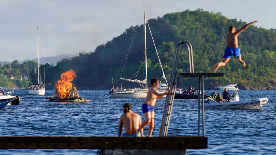 A floating bonfire marks midsummer celebrations as people enjoy the water in the Oslo Fjord by Bjorvika on June 23, 2022. After their long, dark, cold winters, people in Norway like to make the most of their summer days. - Hakon Mosvold Larsen/NTB/AFP/Getty Images