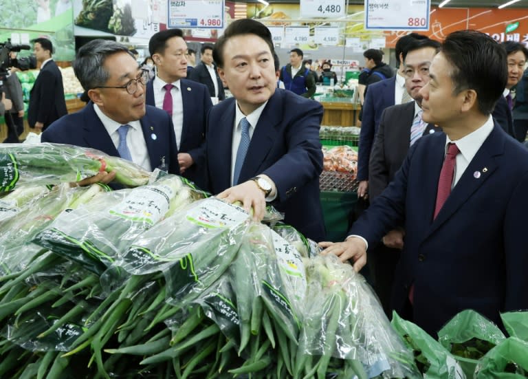 El presidente surcoreano Yoon Suk Yeol (centro) visita un mercado de alimentos en Seúl, el 18 de marzo de 2024 (-)