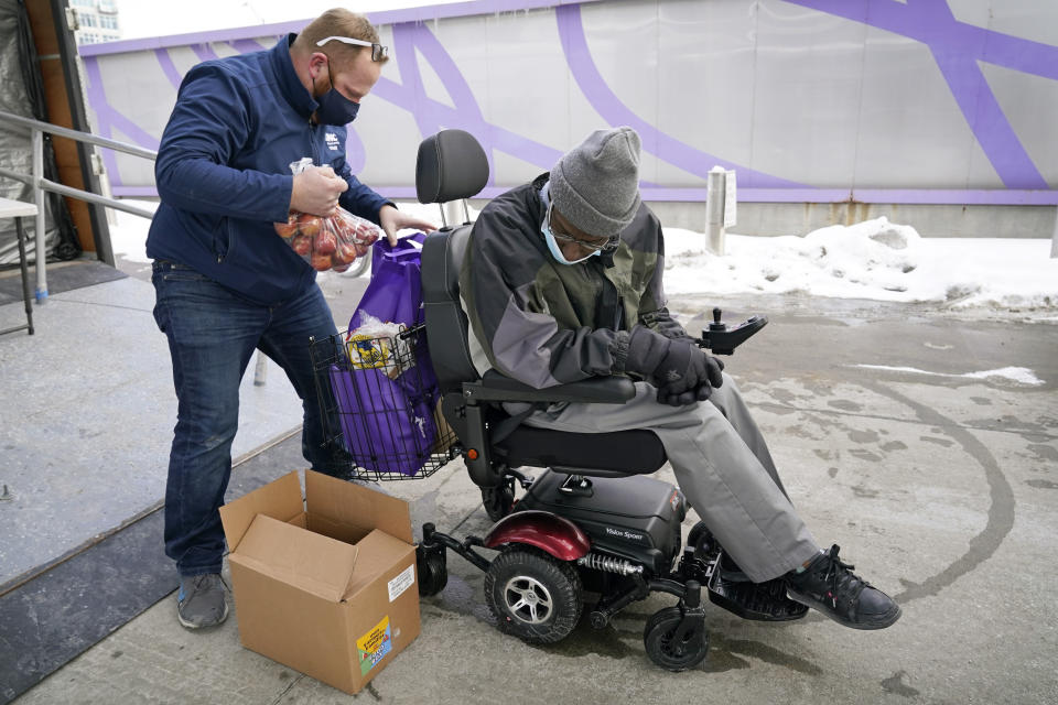 Des Moines Area Religious Council operations manager Joe Dolack, left, loads a Farmers to Families Food Box for Thomas Washington, of Des Moines, Iowa, at a mobile food pantry stop, Thursday, Feb. 18, 2021, in Des Moines, Iowa. Agricultural groups and anti-hunger organizations are pushing the Biden administration to continue the Farmers to Families Food Box program launched by President Donald Trump that spent $6 billion to prevent farmers from plowing under food and instead provide it to millions of Americans left reeling by the coronavirus pandemic. (AP Photo/Charlie Neibergall)