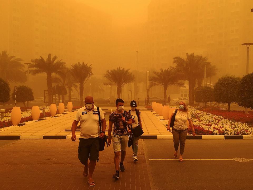 Foreigners wear medical masks as they walk in a street in Dubai amid a sandstorm that engulfed the city on April 02, 2015. AFP PHOTO / MARWAN NAAMANI (Photo credit should read