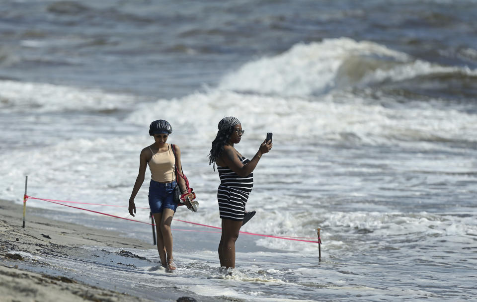 A beachgoer takes pictures at the beach on Saturday, Aug. 31, 2019 in Dania Beach in Florida. The latest forecast says Hurricane Dorian is expected to stay just off shore of Florida and skirt the coast of Georgia, with the possibility of landfall still a threat on Wednesday, and then continuing up to South Carolina early Thursday. (David Santiago/Miami Herald via AP)