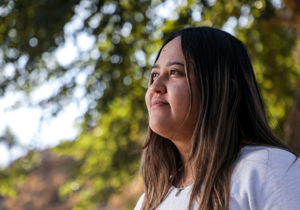 Liz Hernandez poses for a photo at Bloch Cancer Survivors Park, Wednesday, Dec. 1, 2021, in Rancho Mirage, Calif. Liz is caring for her brother Luis’ 3-year-old Chihuahua mix while he is incarcerated. Luis has been in custody since April 2020 after a mental health breakdown. His family misses him daily but says that Christmas, the biggest holiday celebration in their family, will be especially difficult.