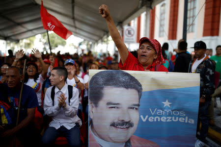 FILE PHOTO: A supporter of Venezuela's President Nicolas Maduro holds a banner depicting him as he takes part in a gathering outside the Miraflores Palace in Caracas, Venezuela January 26, 2019. REUTERS/Carlos Garcia Rawlins/File Photo