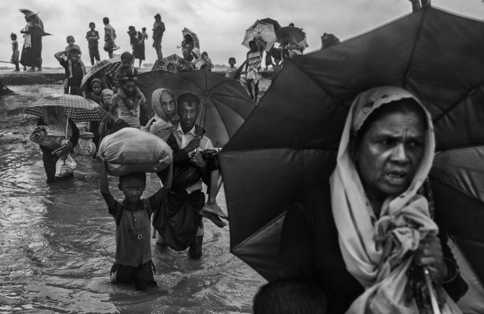 Rohingya refugees carry their belongings as they walk through water on the Bangladesh side of the Naf River after fleeing their village in Myanmar. (Photo: Kevin Frayer via Getty Images)