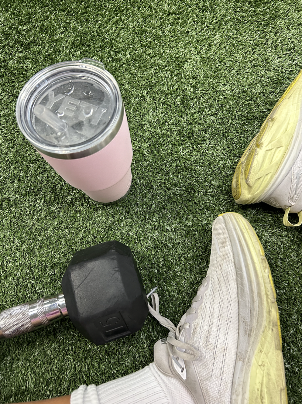 HOKA shoes on grass with a YETI mug and weight.