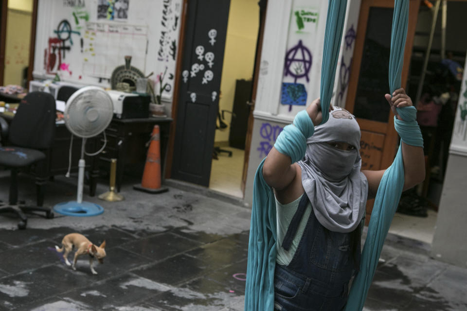 Una niña de 10 años víctima de abusos sexuales, que se cubre la cara para proteger su identidad, posa para una fotografía mientras juega con telas para acrobacias aéreas en el interior de la sede de la Comisión Nacional de Derechos Humanos, donde vive con su madre, quien también sufrió abusos cuando era niña, luego de que activistas feministas ocupasen el inmueble y lo convirtiesen en un refugio, en la Ciudad de México, el 17 de noviembre de 2020. La madre de la niña, Erika Martinez, dijo que hace tres años denunció ante la fiscalía para delitos sexuales que su hija, que entonces tenía 7, fue abusada por su cuñado, pero el hombre sigue libre. (AP Foto/Ginnette Riquelme)