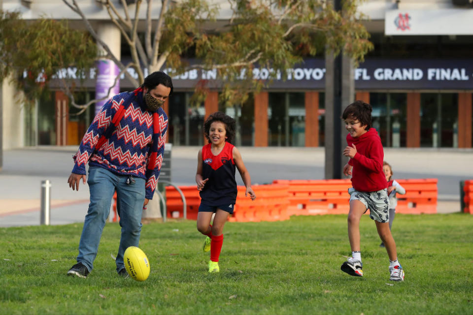Melbourne supporters play kick to kick outside the MCG as they prepare to watch the AFL Grand Final, played at Optus Stadium in Perth, at East Melbourne in Melbourne, Australia. 