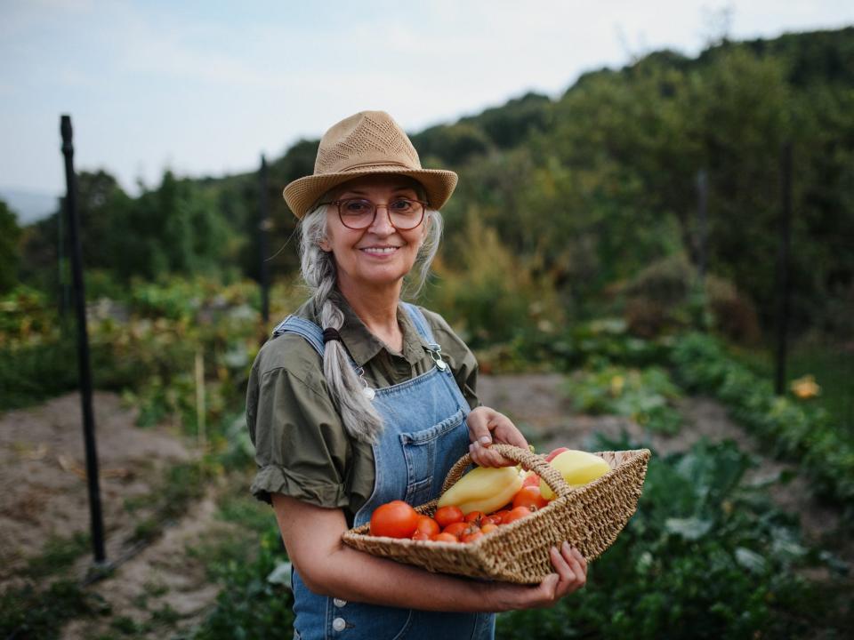 Single woman in a field carrying a basket of vegetables