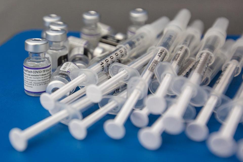 Syringes and vials of Pfizer-BioNTech COVID-19 vaccine are seen on a work surface during a drive-thru vaccination clinic at St. Lawrence College in Kingston, Ont., Dec. 18, 2021.